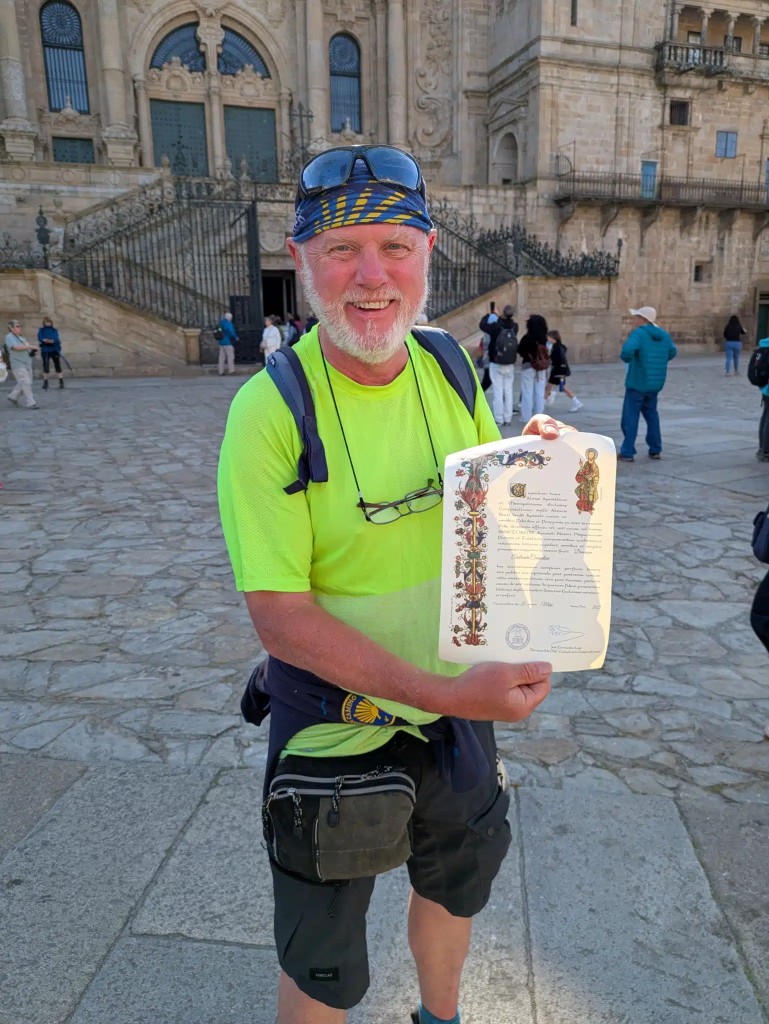 Andrew Considine holding his Camino Compostela certificate in Santiago de Compostela